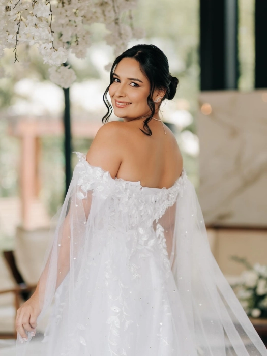 Noiva com vestido de renda ombro a ombro, coque baixo e maquiagem natural