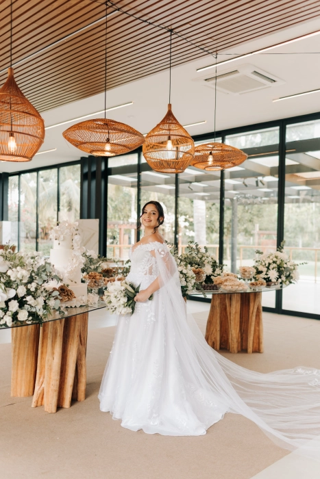 Noiva com vestido de tule bordado e cauda longa no salão de festas decorado